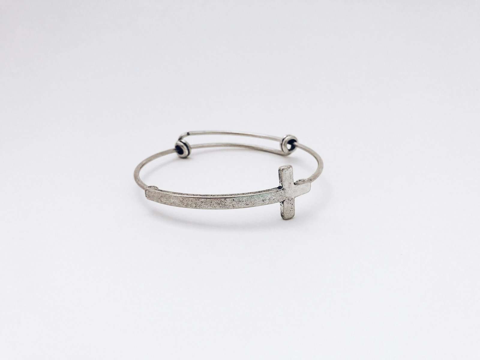 closeup photo of silver-colored cross bangle