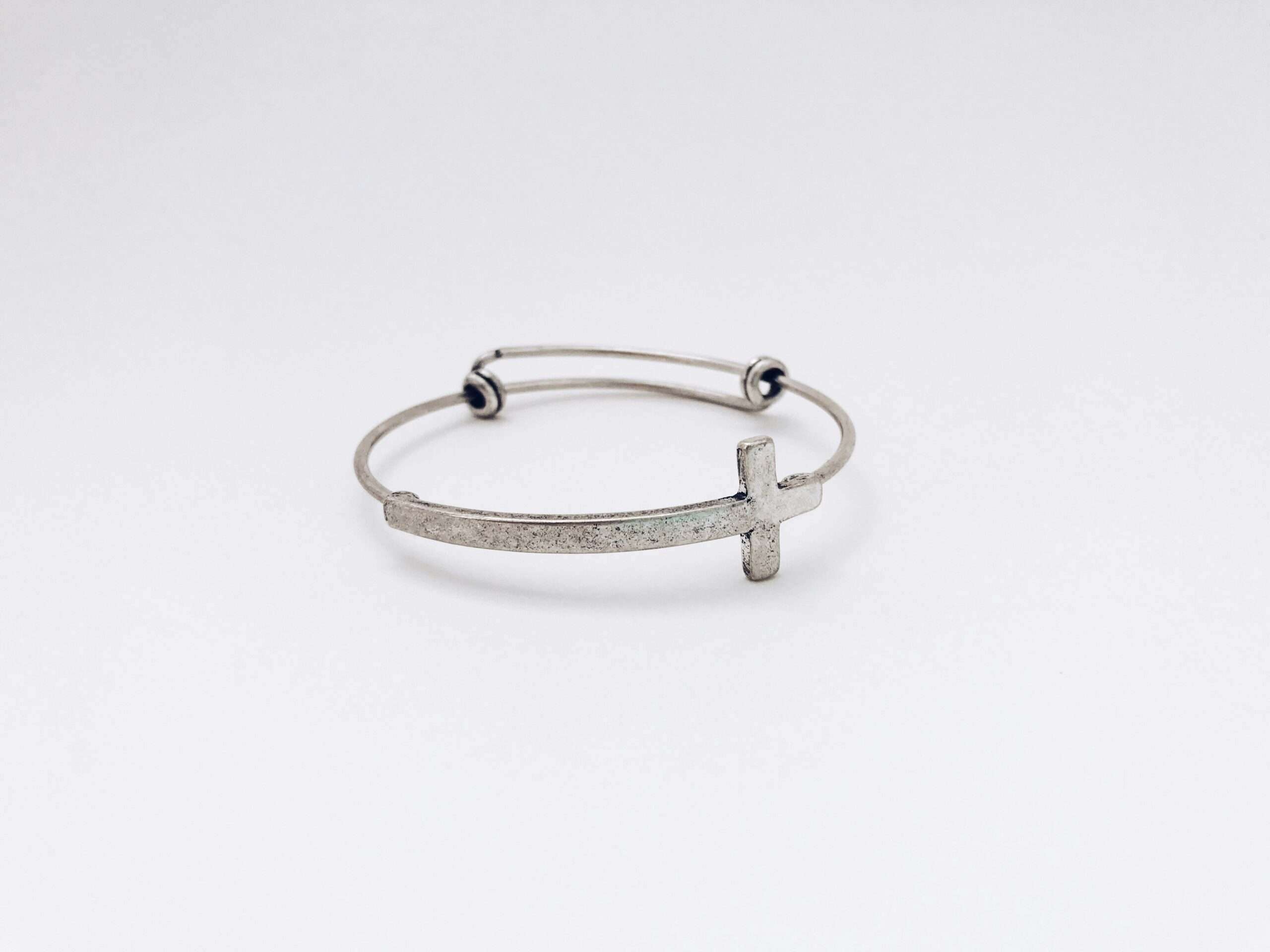 closeup photo of silver-colored cross bangle